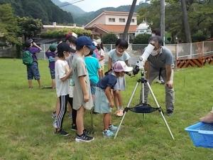 特殊なフィルターの望遠鏡を子どもたちが見ている様子です