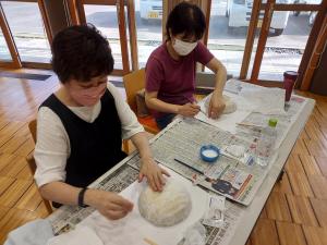 小さなかごに和紙を張り付けている受講生の様子です