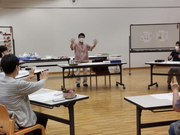 講座の前に講師が手をほぐす運動を受講生にさせている様子です