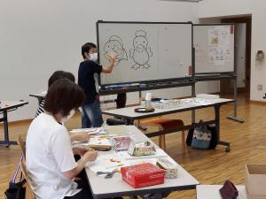 講師がパーツの絵で作り方の説明をしている様子です