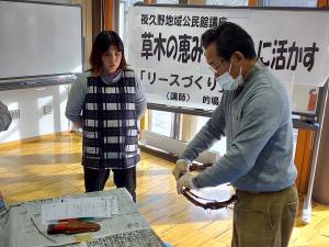 講師がブドウのつるをリースに形作っている様子です