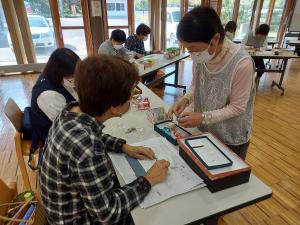 講師が個人指導で飾りものの説明をしている様子です