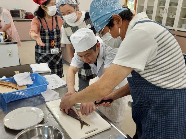 講師が魚のさばき方を教えている様子です