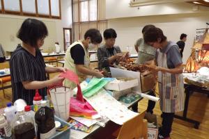 白い和紙の上に貼る色のついた和紙を選んでいる様子です
