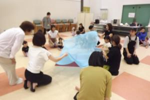 大きな布を使ってみんなで楽しく遊んでいる様子です