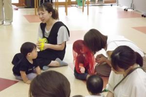 幼児がスカーフをかぶせてもらって喜んでいる様子です