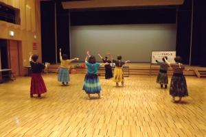 舞台の下で衣装を着けてフラダンスの練習をしている様子です
