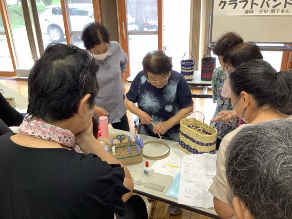 講師が大きなかごの編み方を説明している様子です