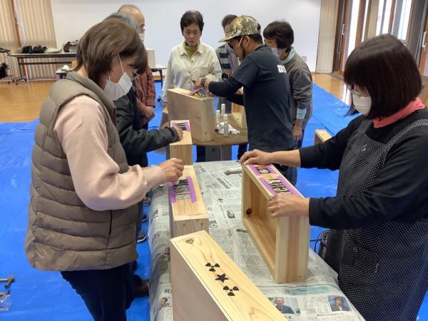 木箱にステンシルの手法で文字を描いている様子です