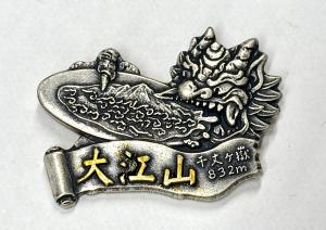大江山の山バッジ。銀色で、鬼が雲海を食べている絵柄の下に、大江山と金色で記載してある。