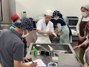 講師が鯵のさばき方を説明されている様子です