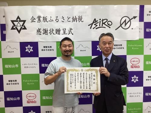感謝状を持って並ぶ株式会社ナンバーホールディングスの川名代表と大橋市長